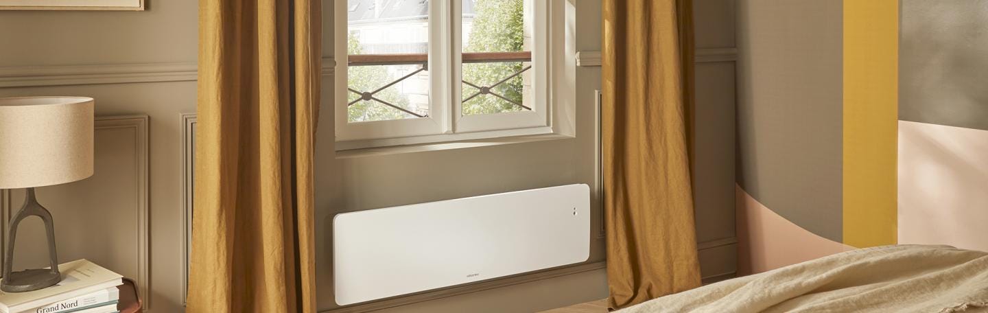 Radiateur électrique à inertie fonte Nirvana+ Atlantic format plinthe dans une chambre contemporaine.