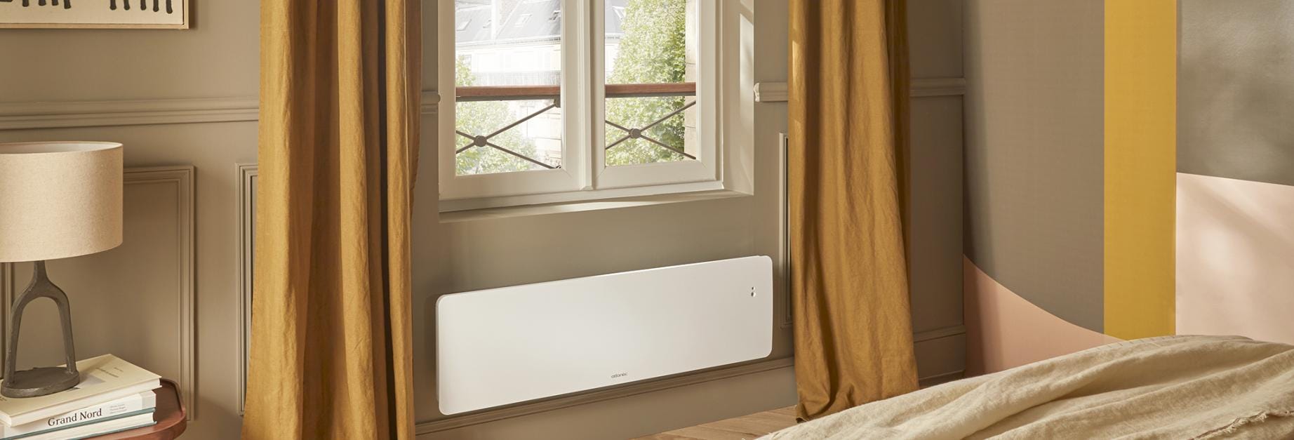 Radiateur électrique à inertie fonte Nirvana+ Atlantic format plinthe dans une chambre contemporaine.